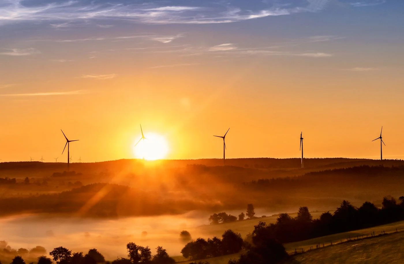 Wind turbines across a landscape at sunrise, a stock photograph